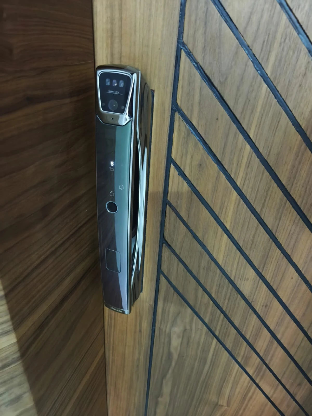 Serrure intelligente K10 Face ID installée sur une porte en bois à lames verticales au Maroc, réalisation Binaa.