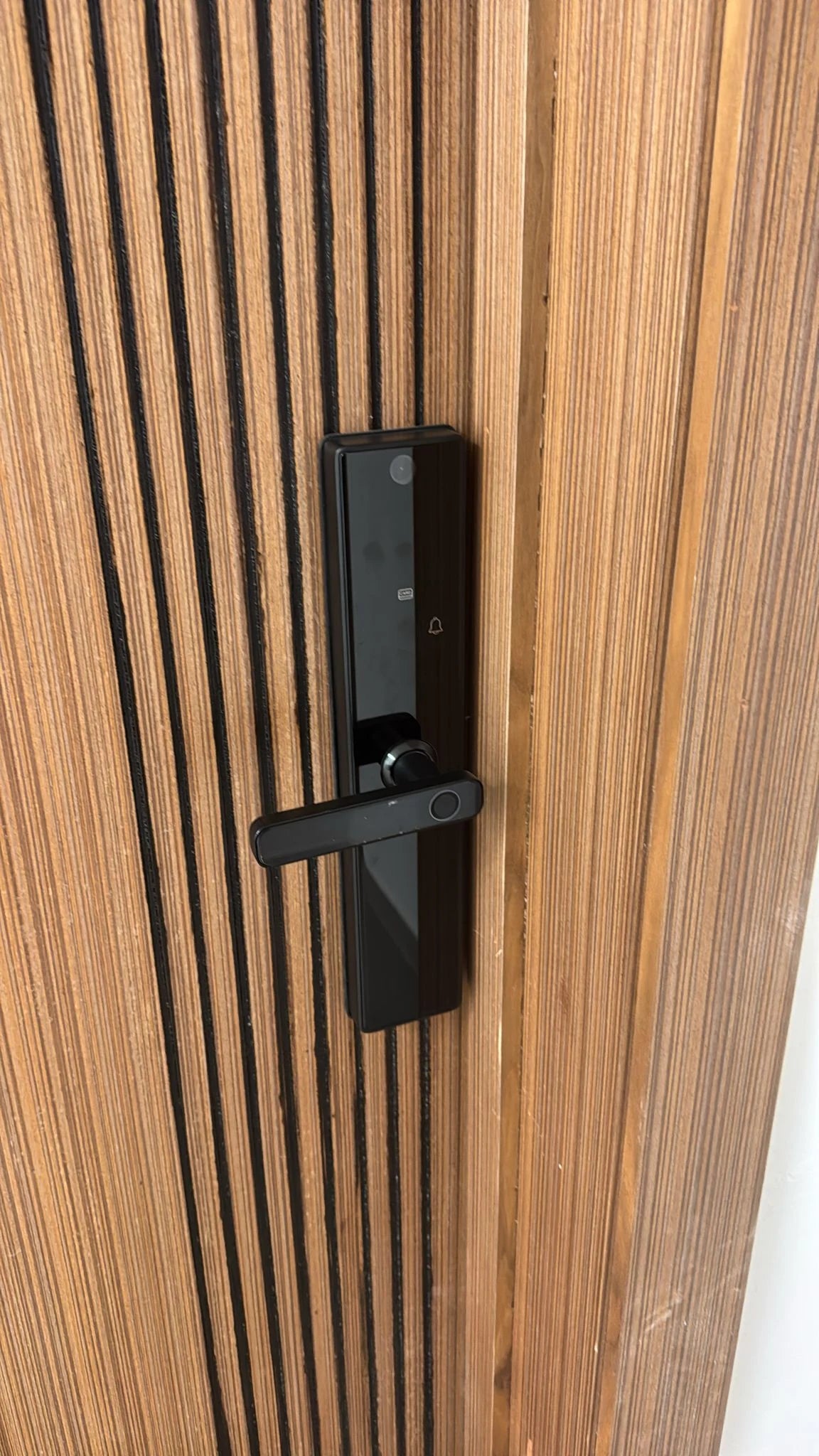 Serrure intelligente M1 Pro installée sur une porte en bois à lames verticales au Maroc, réalisation Binaa.